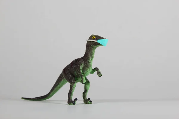 Zbliżenie Zielonej Zabawki Dinozaura Noszącej Ochronną Maskę Twarzy Szarym Tle — Zdjęcie stockowe