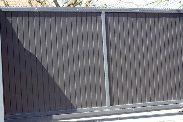 A closeup of a solid aluminum driveway gate panels of a house