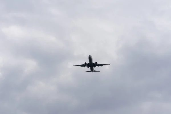 在多云的天空中飞行的飞机的低角度镜头 — 图库照片