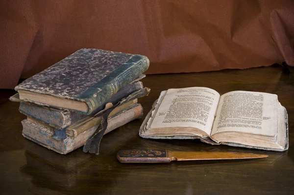 看一下翻开的书和一把古旧的小刀旁的一堆古色古香的书籍 — 图库照片