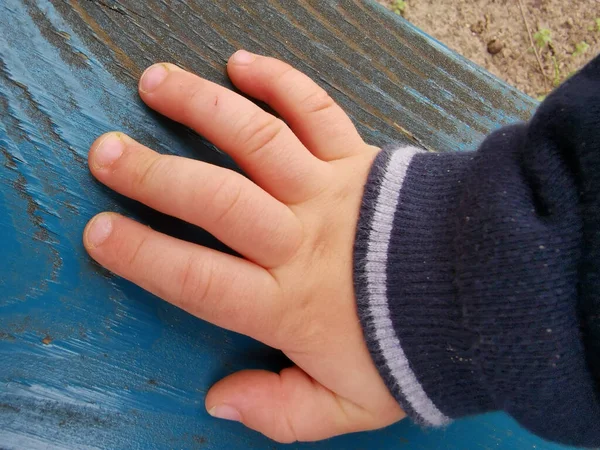 Крупный План Руки Ребенка Теплым Рукавом Свитера Синей Окрашенной Древесине — стоковое фото