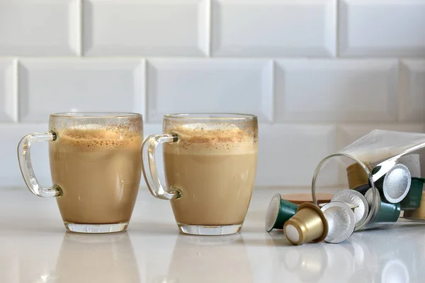 Egy Közeli Kép Két Pohár Házi Cappuccinóról Kapszulákkal Fehér Pulton — Stock Fotó