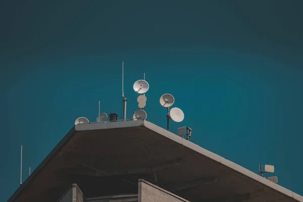 暗い青を背景に屋根の上にアンテナ付きの建物のクローズアップショット — ストック写真