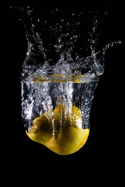 梨子在水中的垂直拍 在黑暗偏僻的背景上喷出水花 — 图库照片