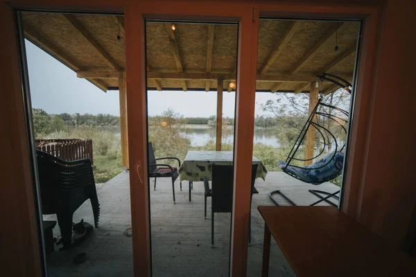 透明窗户上的木制框架 用小桌子和蛋椅展示室外休憩区 — 图库照片