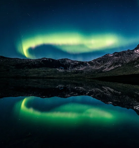 Ett Landskap Norrsken Ovanför Sjö Och Steniga Kullar Kvällen Tromso — Stockfoto