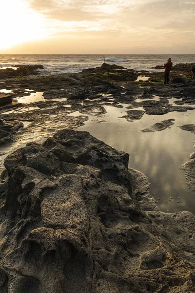 Gün Batımında Balık Tutan Adamla Kayalık Bir Sahilin Dikey Görüntüsü — Stok fotoğraf