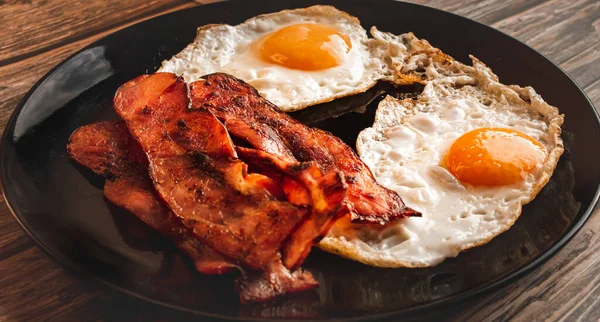特写的早餐镜头 在黑色盘子里放上美味的肉和鸡蛋 — 图库照片