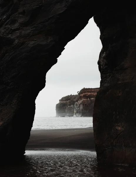 一个通过自然拱门捕获的海岸和悬崖的垂直截图 — 图库照片