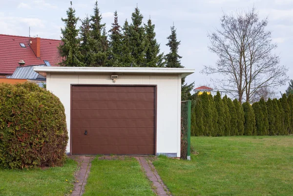 Een Garage Met Bruine Deur Een Groene Tuin Onder Bewolkte — Stockfoto