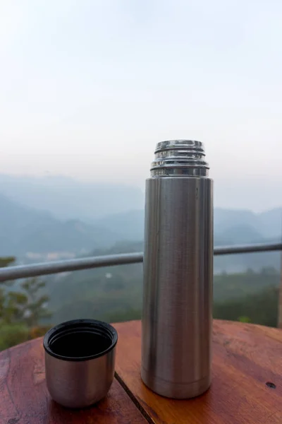 Plano Vertical Termo Plateado Sobre Una Mesa Con Vista Bosque —  Fotos de Stock