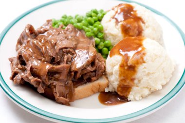 open faced diner style hot beef sandwich with mashed potatoes, gravy and fresh vegetables clipart