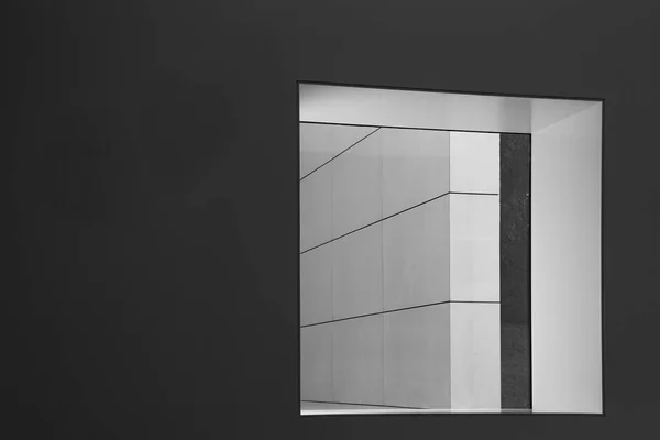 窓のある暗い灰色の壁が斜めの線を持つ白い壁につながり 明快で構造化された要素を持つ現代的な建物 コピースペース — ストック写真