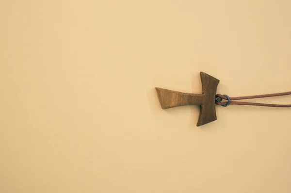 茶色の背景に隔離された木製のタウクロスネックレスのクローズアップショット — ストック写真