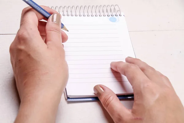 鉛筆で書いた女性の手のクローズアップショットは 支配ノートパッドに書き込みます — ストック写真