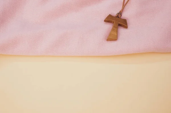 Zbliżenie Drewnianego Naszyjnika Krzyża Tau Różowej Tkaninie Pastelowej Powierzchni Brzoskwini — Zdjęcie stockowe