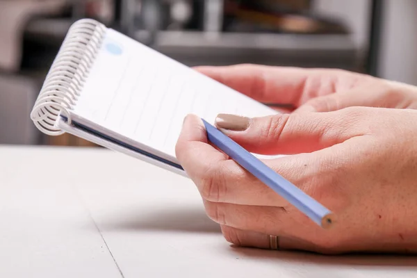 鉛筆で書いた女性の手のクローズアップショットは 支配ノートパッドに書き込みます — ストック写真