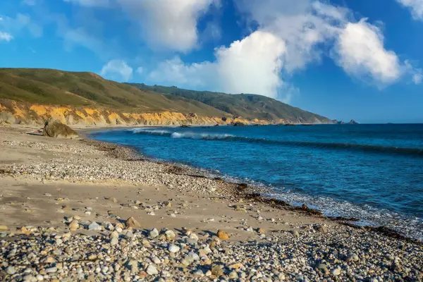 海浪拍打着背景的群山冲刷着海岸 — 图库照片