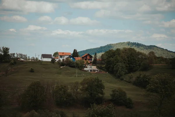 Piękny Widok Rozległe Zielone Wzgórza Kilkoma Domami Zbudowanymi Ich Szczycie — Zdjęcie stockowe