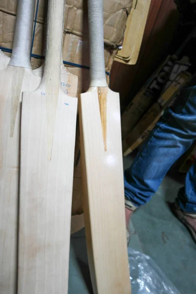 A vertical shot of wooden cricket bats in a factory