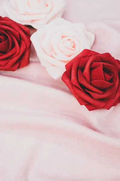 红色和白色玫瑰在皱巴巴的粉色布背景上的垂直照片 带有复制空间 — 图库照片