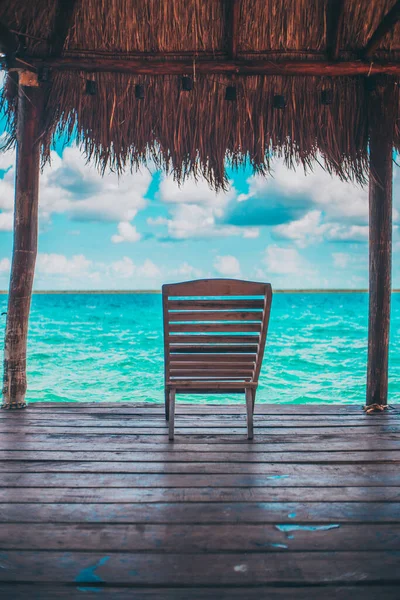 波状のビーチの前で木製の椅子の垂直ショット — ストック写真
