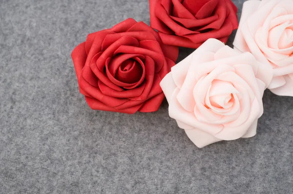 灰色羊毛背景上的一对红玫瑰和一对粉红玫瑰 有复制空间 — 图库照片