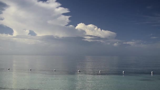 Brede opname van een klein eilandje op het lichaam van de zee in de verte onder een helderblauwe lucht — Stockvideo