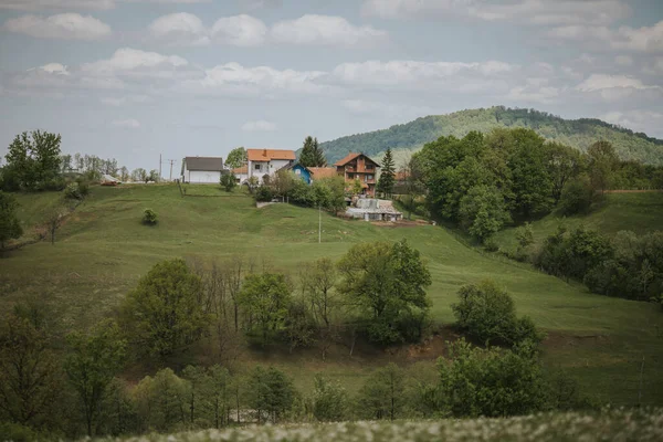 Kilka Domów Zbudowanych Szczycie Wzgórza Drzewami Pod Chmurnym Niebem — Zdjęcie stockowe