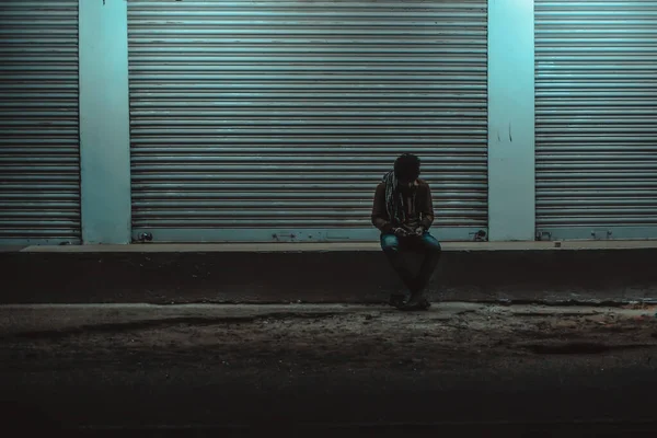 Samotny Człowiek Siedzący Betonowej Powierzchni Oświetlonym Tle Ściany — Zdjęcie stockowe