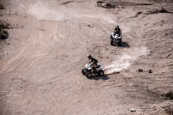 stock image The two people  wearing helmets and drifting on the sandy field with quad bike