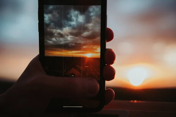 携帯電話で美しい夕日を撮影した男のクローズアップショット — ストック写真