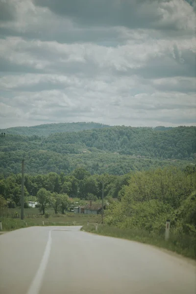 Vertikální Záběr Asfaltové Silnice Obklopený Přírodou Zamračeném Pozadí Oblohy — Stock fotografie
