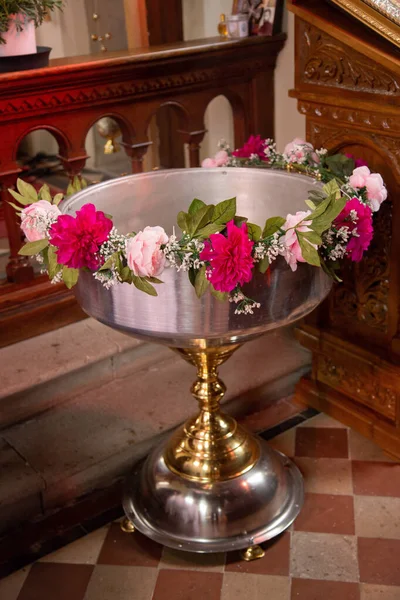 A vertical shot of baptismal font decorated with flowers