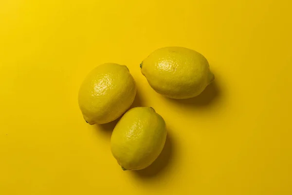 黄色の背景に隔離された3つのレモン — ストック写真