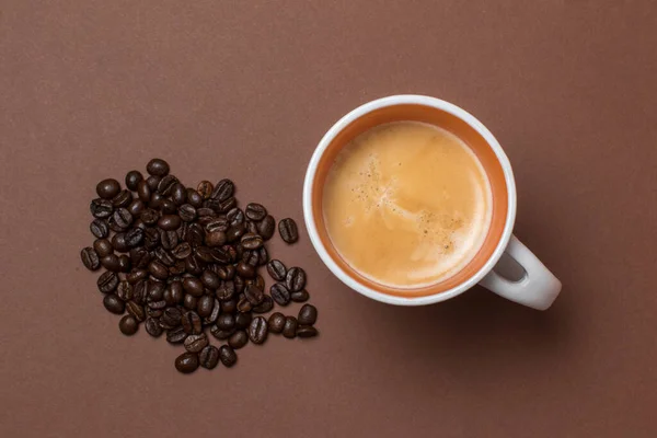 coffee in a white coffee cup and many coffee beans placed in a brown background