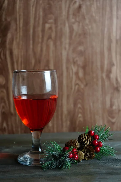 テーブルの上の赤ワインのグラスに装飾的なホリーベリーの垂直ショット — ストック写真