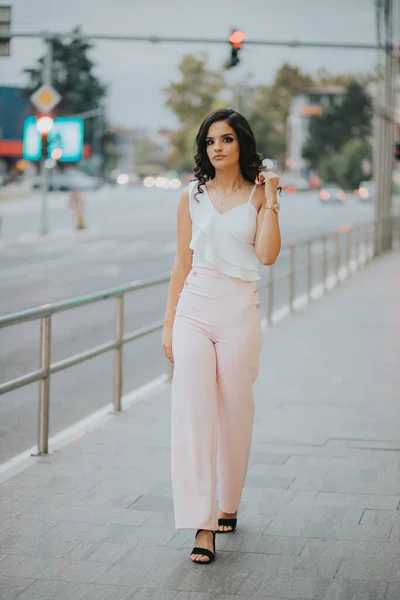 Young Brunette Curly Female Model Walking Sidewalk Wearing Elegant Pink — стоковое фото