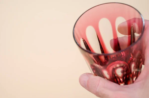 Uma Mão Masculina Segurando Copo Vermelho Vazio Isolado Fundo Rosa — Fotografia de Stock