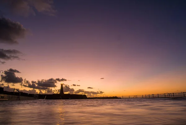 夕焼け空を背景に灯台のある美しい海 — ストック写真