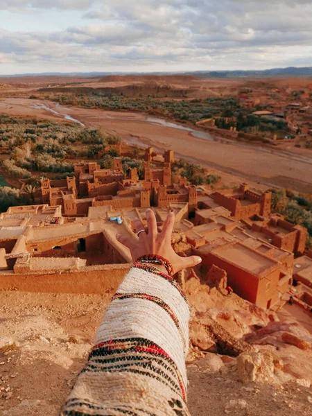 A person reaching with hand to the Ait Benhaddou fortified village buildings