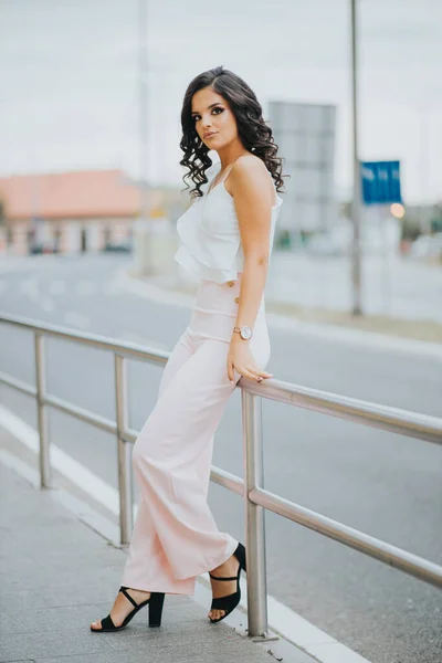 一位漂亮的女性 身穿华丽的粉色和白色服装 靠着城市街道围栏 — 图库照片