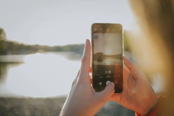 Una Persona Tomando Fotos Puesta Sol Sobre Lago Con Teléfono — Foto de Stock