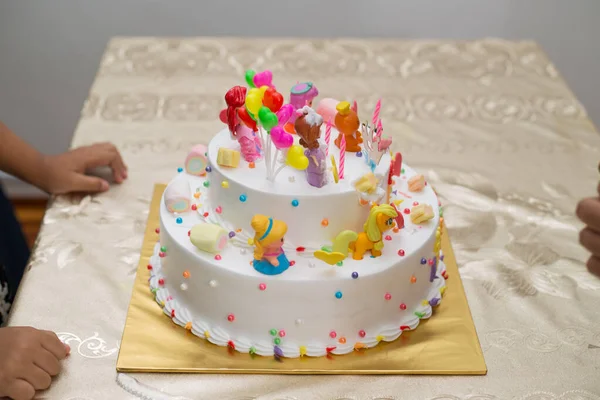 在色彩艳丽的生日蛋糕旁边的桌子上 有一张特写镜头 上面有卡通人物 — 图库照片