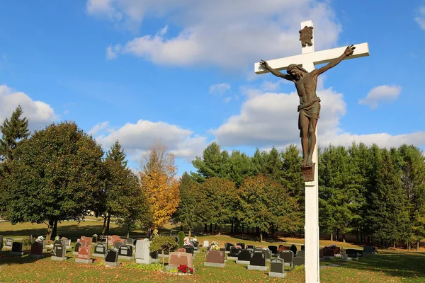 Bronze sculpture of Jesus Christ on a white wooden cross at a cemetery