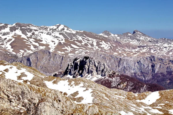 澄んだ青い空の下で雪に覆われた岩肌と山々の豪華な風景 — ストック写真