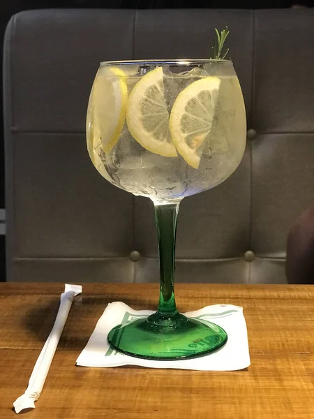 Colpo Verticale Bicchiere Con Acqua Ghiacciata Fette Limone Tavolo Legno — Foto Stock