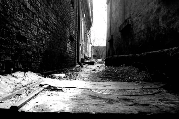 Grayscale Shot Narrow Alleyway Old Town Manhole Foreground — Zdjęcie stockowe