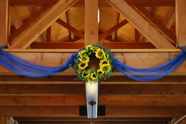 A low angle shot of a wooden ceiling decorated with artificial sunflowers and blue transparent cloth