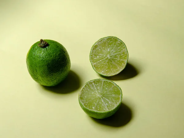 Eine Ganze Limette Und Zwei Hälften Auf Grünem Hintergrund — Stockfoto